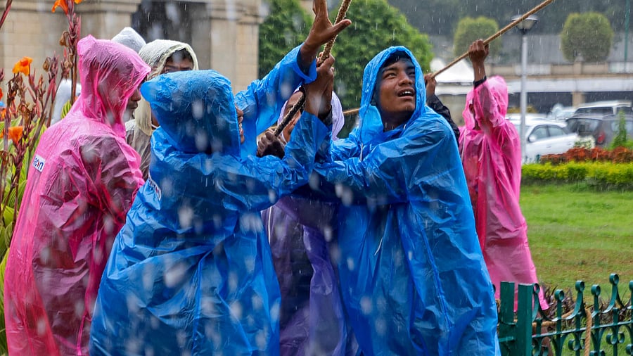<div class="paragraphs"><p>Workers amid rains at the Vidhana Soudha on Thursday. </p></div>