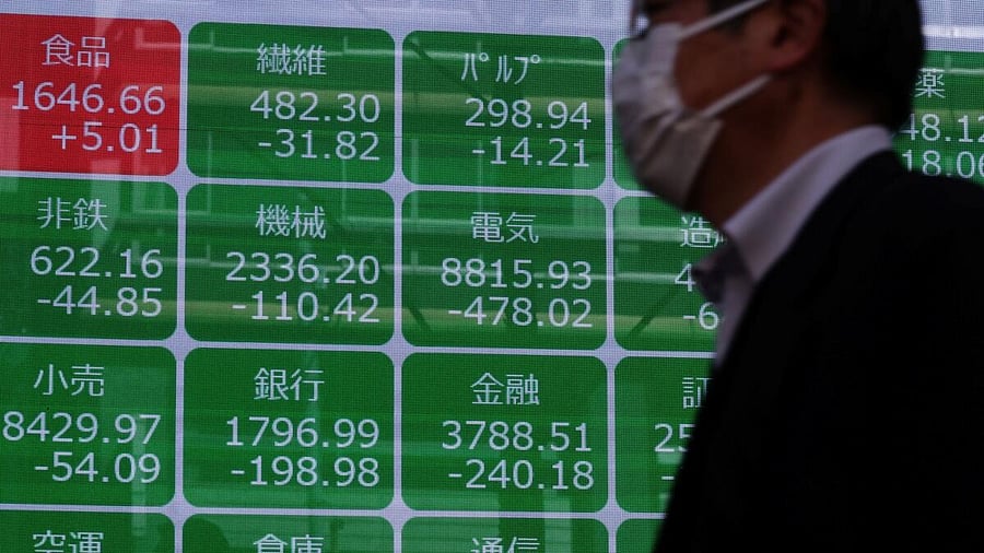 <div class="paragraphs"><p>A man walks past a screen displaying the bank and financial sector indexes outside a brokerage in Tokyo.</p></div>
