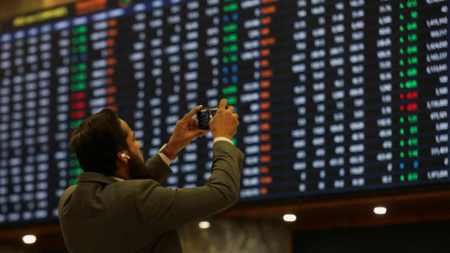 <div class="paragraphs"><p>A man takes a photo of the electronic board displaying share prices during a trading session at the Pakistan Stock Exchange</p></div>