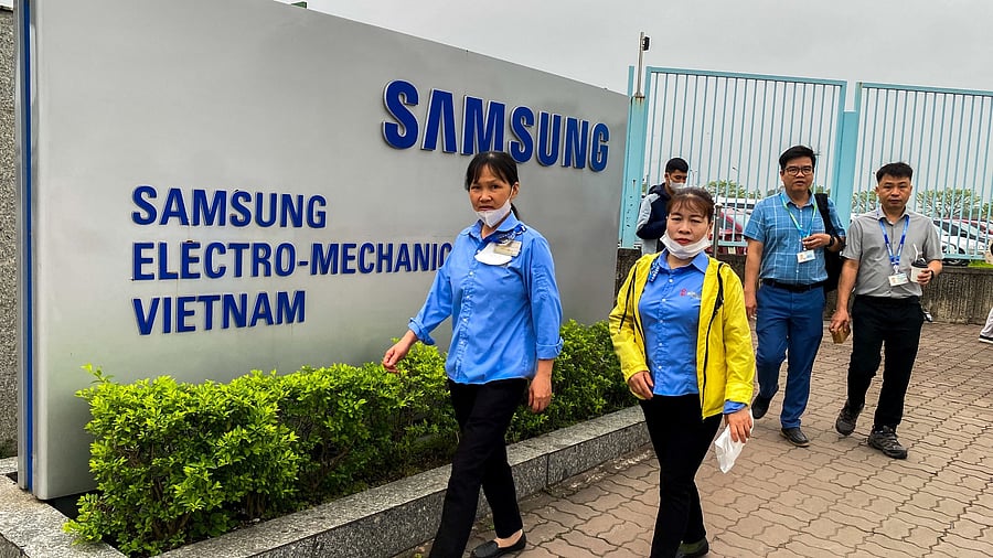 <div class="paragraphs"><p>People walk past a gate of the Samsung Electro-Mechanics factory, following  US President Donald Trump's imposition of a tariff rate of 46 per cent on Vietnam, in Thai Nguyen province, Vietnam.</p></div>