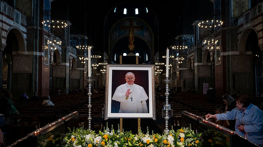 <div class="paragraphs"><p>Catholics pray in front of a portrait of Pope Francis.</p></div>