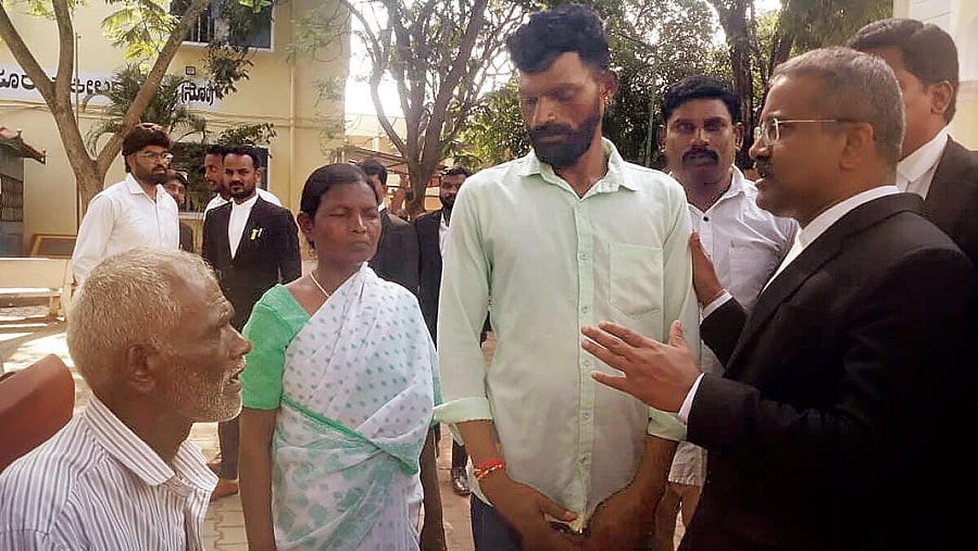 Advocate B S Pandu Poojari explains judgement to family of Suresh at court premises in Mysuru on Wednesday. DH Photo