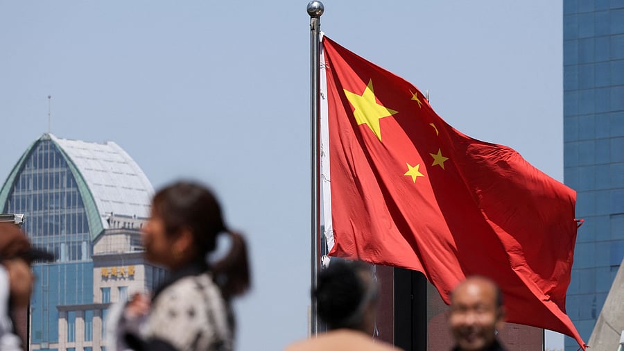 <div class="paragraphs"><p>A Chinese national flag flies as people walk on a pedestrian bridge at the Lujiazui financial district in Shanghai, China.</p></div>