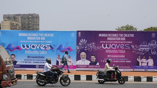 <div class="paragraphs"><p>Commuters pass by hoardings put up for the World Audio Visual &amp; Entertainment Summit (WAVES 2025), in Mumbai.</p></div>