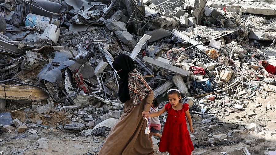 <div class="paragraphs"><p>A woman and child walk among debris, aftermath of Israeli strikes at the area.</p></div>