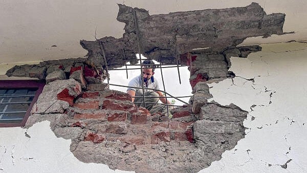 <div class="paragraphs"><p>A man looks through a damaged portion of a house after heavy firing and shelling by Pakistan military overnight across the Line of Control and International Border, at Mendhar area of Poonch district, Jammu and Kashmir, Wednesday, May 7, 2025.</p></div>