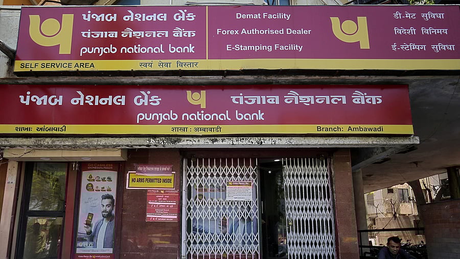 <div class="paragraphs"><p>FILE PHOTO: A man reads a newspaper outside a branch of Punjab National Bank (PNB) in Ahmedabad.</p></div>