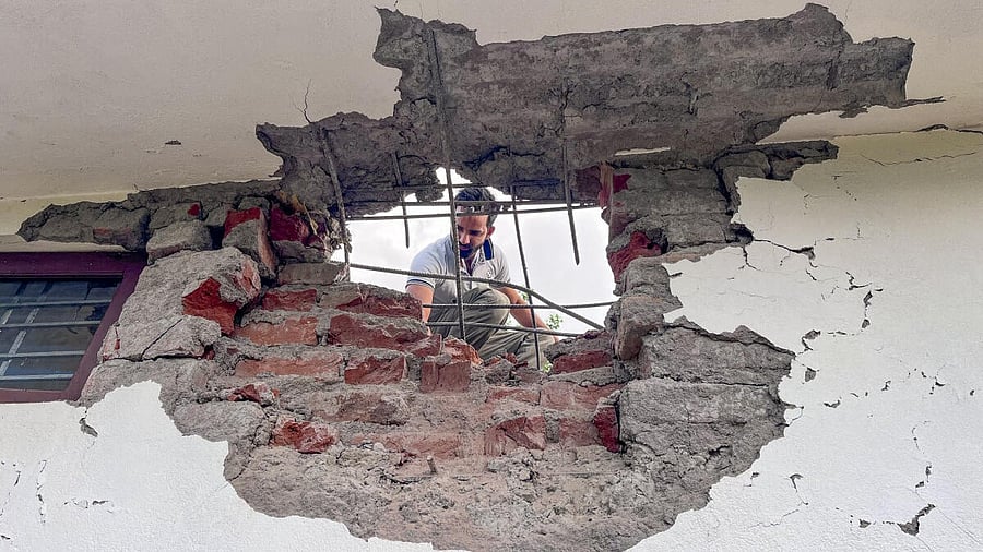 <div class="paragraphs"><p>A man looks through a damaged portion of a house after heavy firing and shelling by Pakistan military overnight across the Line of Control and International Border, at Mendhar area of Poonch district, Jammu and Kashmir, Wednesday, May 7, 2025.</p></div>