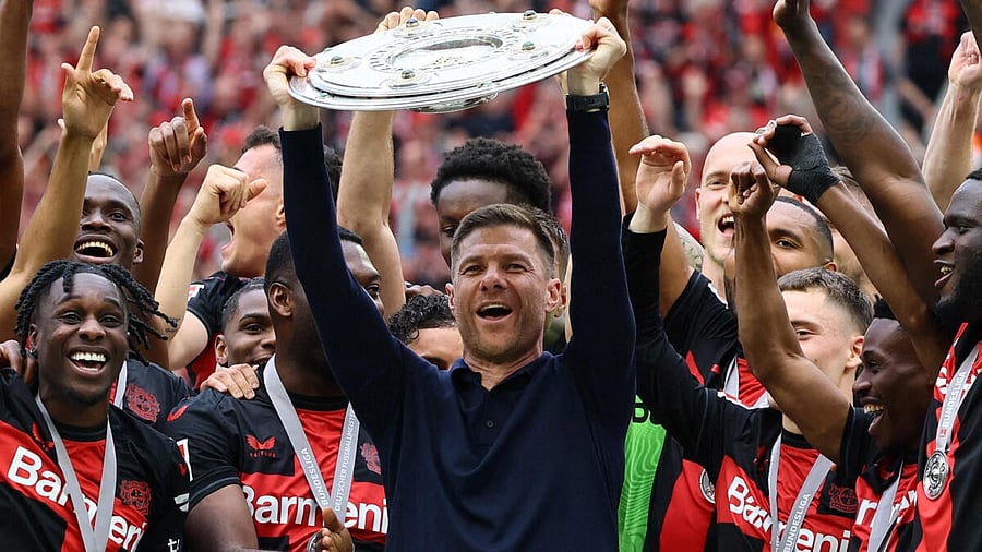 <div class="paragraphs"><p>Bayer Leverkusen coach Xabi Alonso celebrates with the trophy after winning the Bundesliga and going unbeaten.</p></div>