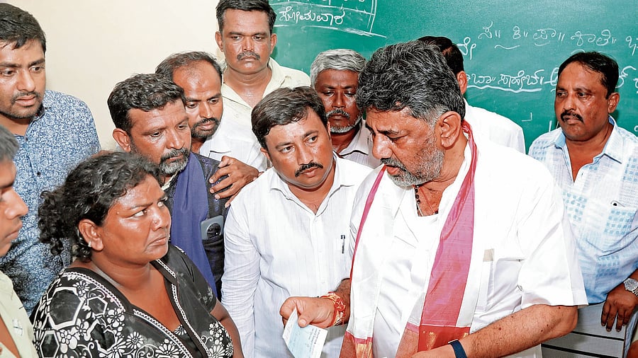 Deputy Chief Minister D K Shivakumar presents compensation cheques to the parents of the girl who was allegedly raped and murdered. 