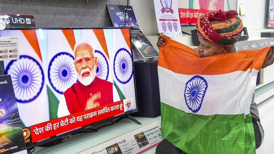 <div class="paragraphs"><p> A man holds the national flag as he watches the live telecast of Prime Minister Narendra Modi's address to the Nation, in Bikaner, Monday, May 12, 2025.</p></div>