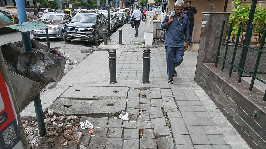 <div class="paragraphs"><p>Pedestrians struggle to walk along a broken footpath on MG Road. </p></div>