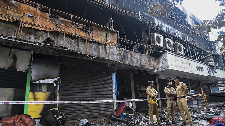 <div class="paragraphs"><p>Kerala Police personnel stand near the charred remains of a textile shopping hub where a fire broke out on Sunday, in Kozhikode.</p></div>