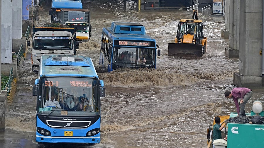<div class="paragraphs"><p>Buses and heavy vehicles wave through flooded streets at Silk Board junction after heavy rains in Bengaluru on Monday, May 19, 2025.</p></div>