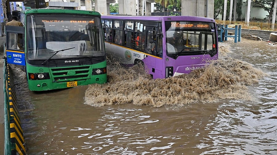 <div class="paragraphs"><p>Buses and heavy vehicles wave through flooded streets at Silk Board junction after heavy rains in Bengaluru on Monday, May 19, 2025.</p></div>