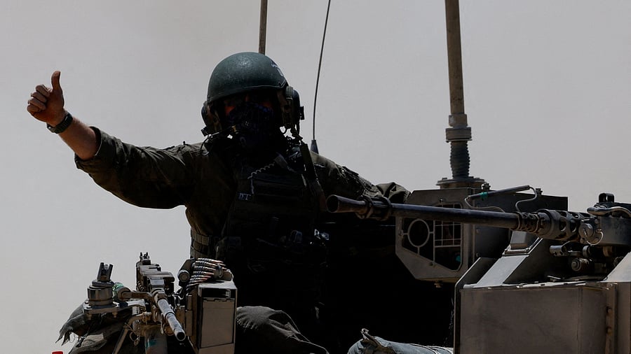 <div class="paragraphs"><p>An Israeli soldier gestures as military vehicles drive their way from the Israeli side of the Israel-Gaza border into Gaza, as seen from Israel, May 20, 2025. </p></div>