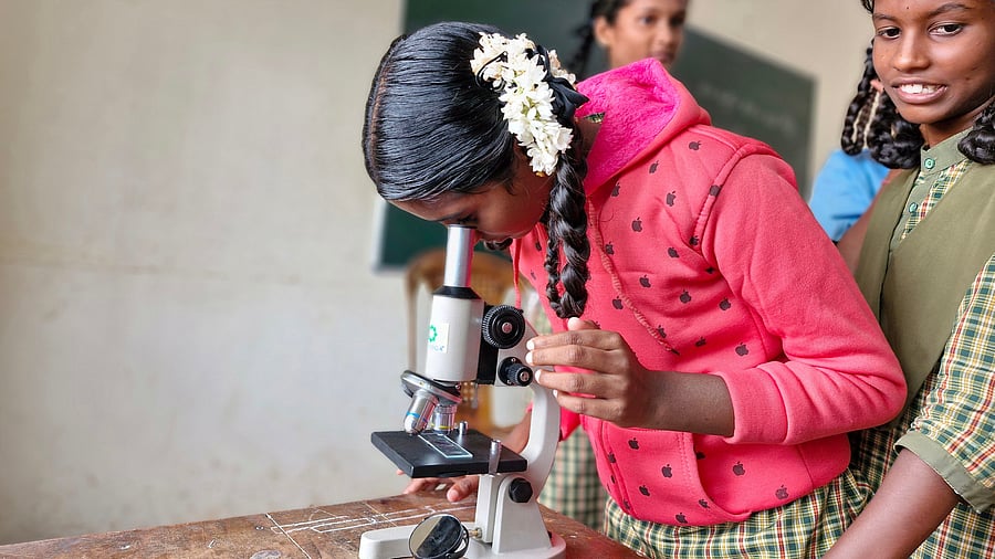 Students look into a microscope during a lab session.