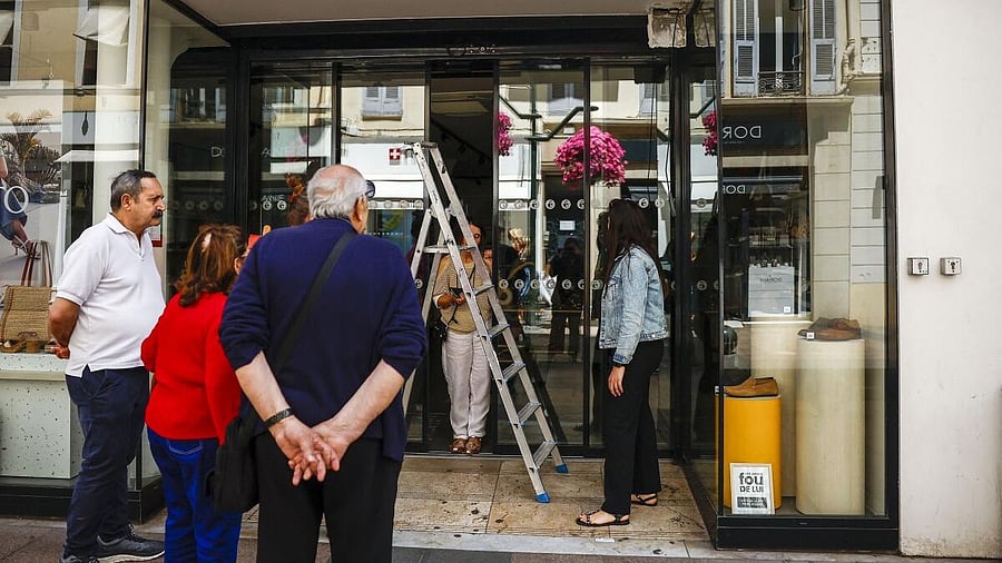 <div class="paragraphs"><p>Workers try to enter a shop whose automatic doors have been blocked following a major electricity outage, during the 78th Cannes Film Festival in Cannes</p></div>