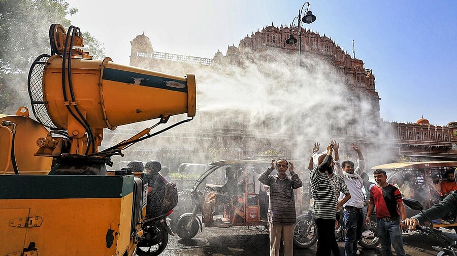 <div class="paragraphs"><p>People stand near a vehicle spraying mist for respite from the scorching heat on a hot summer day, at Hawa Mahal in Jaipur.</p></div>