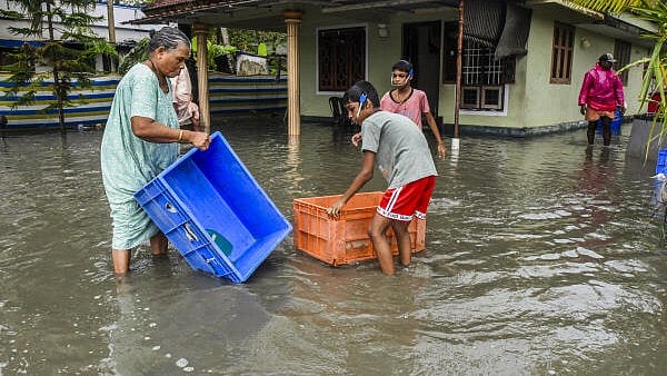 <div class="paragraphs"><p>People prevent their belongings from being carried away by water at a flooded residential area after heavy monsoon rainfall, in Kochi.</p></div>