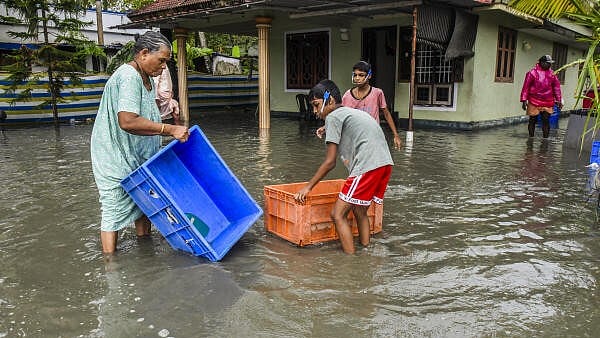 <div class="paragraphs"><p>People prevent their belongings from being carried away by water at a flooded residential area after heavy monsoon rainfall, in Kochi.</p></div>