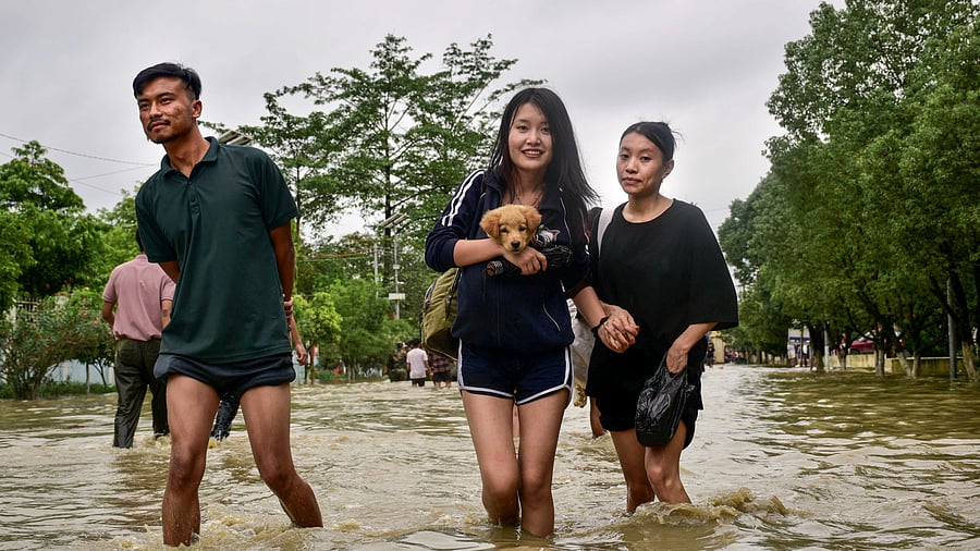 <div class="paragraphs"><p>Women carrying their pet and belongings shift to a safer place from a flooded area after heavy rainfall, in Imphal East district, Manipur, Sunday, June 1, 2025.</p></div>