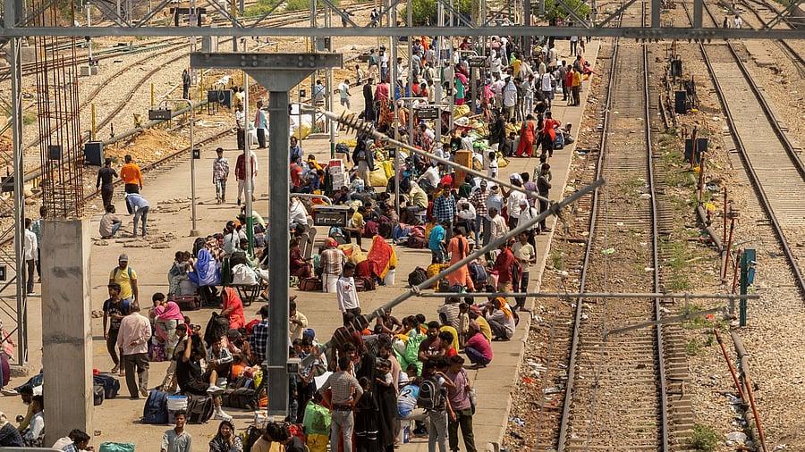 <div class="paragraphs"><p>People sit on a platform as they wait to board a train at a railway station in Jammu. </p></div>
