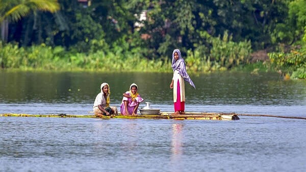 <div class="paragraphs"><p>Women use a makeshift raft to cross a flooded area, in Kamrup district of Assam, Friday, June 6, 2025.</p></div>