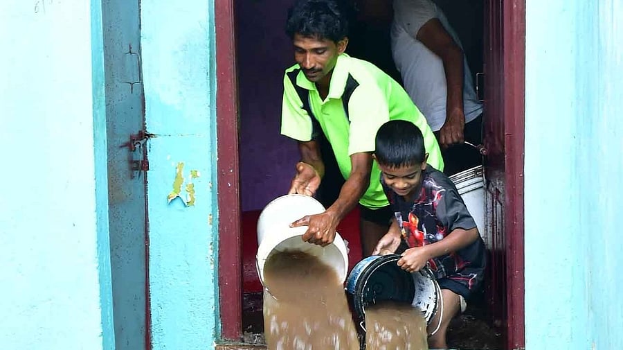 Children lend a helping hand in clearing rainwater from a house after a sharp spell left several homes flooded at Haveripet in Dharwad on Sunday.