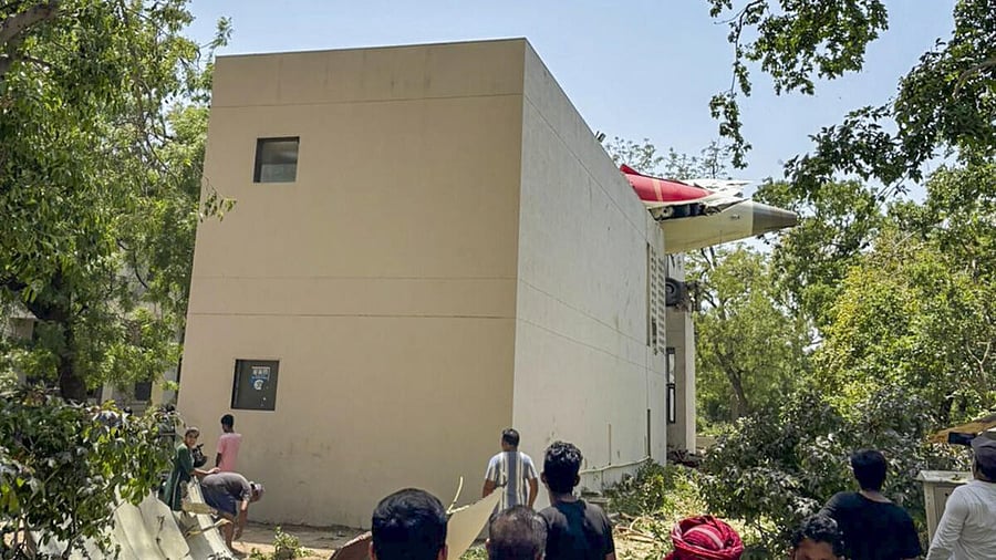 <div class="paragraphs"><p>People look at the remains of the Air India plane that crashed moments after taking off from the airport, lying on a residential building, in Ahmedabad, Thursday, June 12, 2025.</p></div>