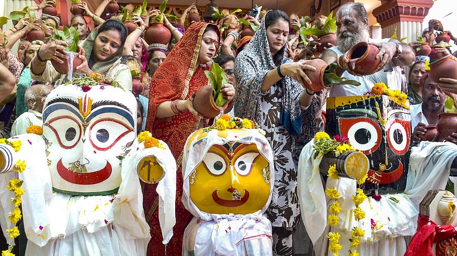 <div class="paragraphs"><p>A priest along with women devotees performs ritual bathing of Lord Jagannath, Balabhadra and Subhadra as part of the upcoming Rath Yatra festival, at Jagannath Temple.</p></div>