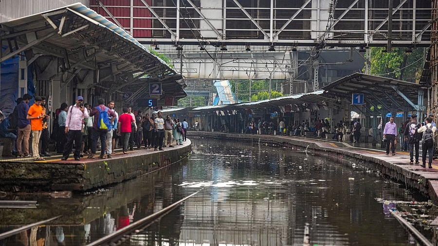 <div class="paragraphs"><p>Passengers wait for trains at a waterlogged railway station, during rains, in Mumbai.</p></div>