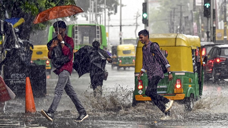 <div class="paragraphs"><p>People cross a road amid heavy rains, in Kerala.</p></div>