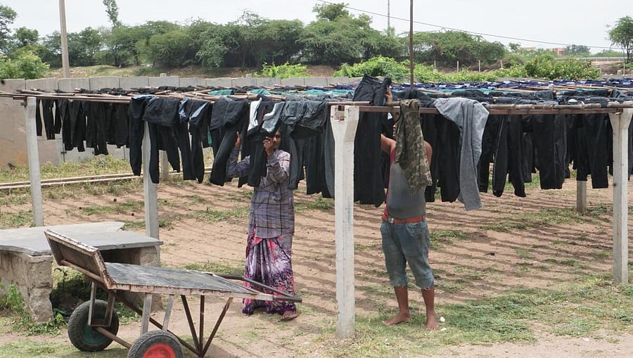 Workers put out dyed jeans garments for drying at a dyeing unit in Ballari district.   