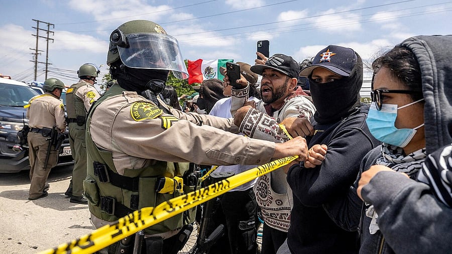 <div class="paragraphs"><p>A Los Angeles County Sheriff's deputy holds back protesters following multiple detentions by Immigration and Customs Enforcement (ICE), in the Los Angeles County city of Compton</p></div>