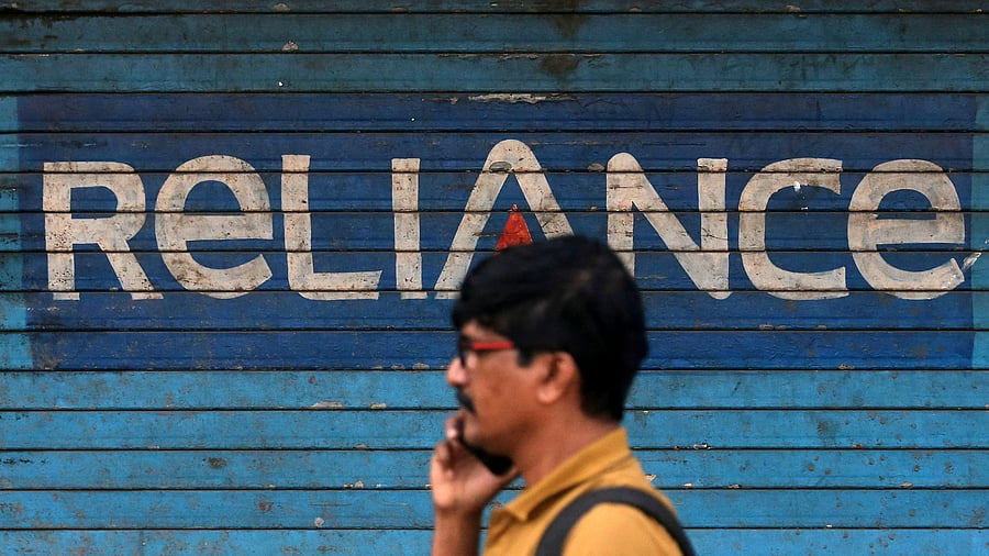 <div class="paragraphs"><p>A man speaks on his mobile phone as he walks past a closed shop painted with an advertisement of Reliance Communications in Mumbai. </p></div>