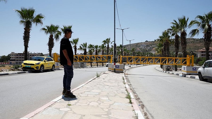 <div class="paragraphs"><p>A Palestinian man stands near a closed gate at the entrance of Turmus Ayya village near Ramallah, in the Israeli-occupied West Bank.</p></div>