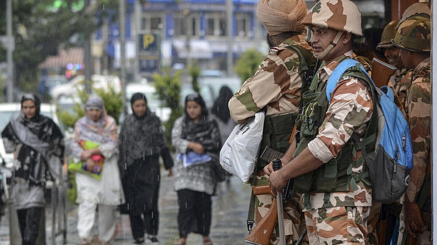 <div class="paragraphs"><p>Security personnel stand guard under a shop's roof amid rain, in Srinagar, Monday, July 7, 2025.</p></div>