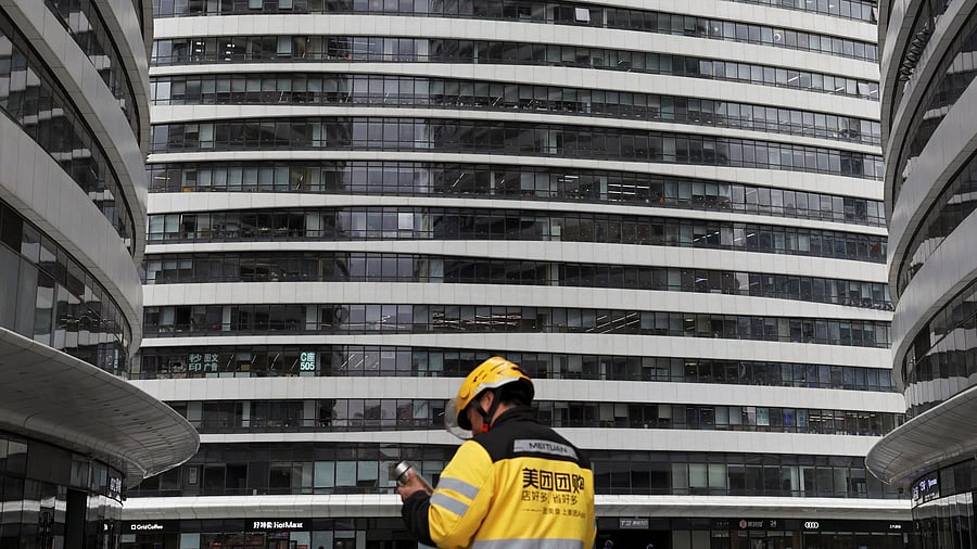 <div class="paragraphs"><p>A Meituan delivery worker walks among office towers in Beijing, China. Image for representational purposes.</p></div>