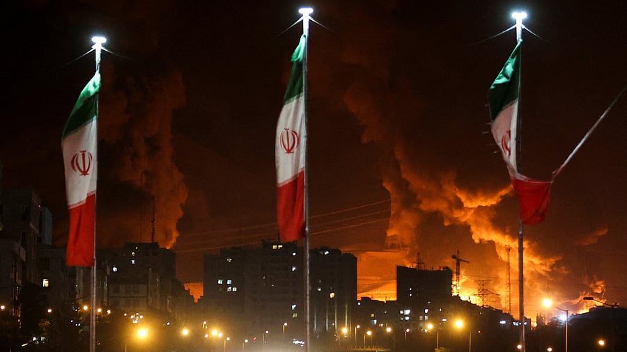 <div class="paragraphs"><p>Iranian flags fly as fire and smoke from an Israeli attack on Sharan Oil depot rise, following Israeli strikes on Iran, in Tehran, Iran, June 15, 2025.</p></div>