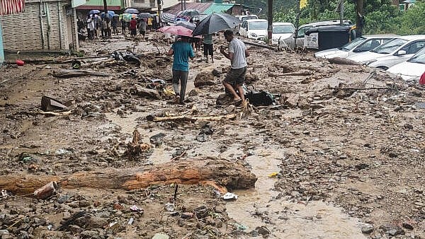 <div class="paragraphs"><p>People walk through the debris after flash floods triggered by heavy rainfall, in Mandi, Himachal Pradesh.</p></div>