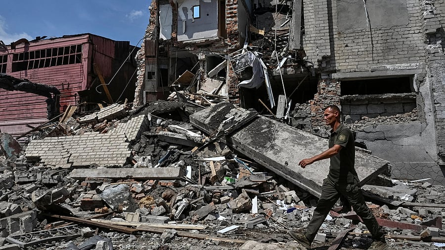 <div class="paragraphs"><p>A serviceman walks at the site hit by a Russian air strike</p></div>
