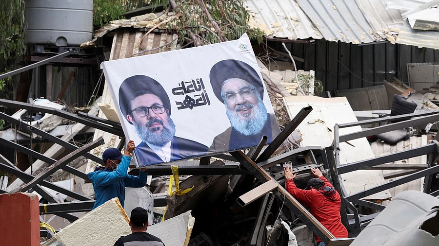 <div class="paragraphs"><p>A man carries a picture of the late Hezbollah leaders Hassan Nasrallah and Hashem Safieddine at a damaged site in the aftermath of Israeli strikes in Beirut's southern suburbs, Lebanon, April 28, 2025. </p></div>