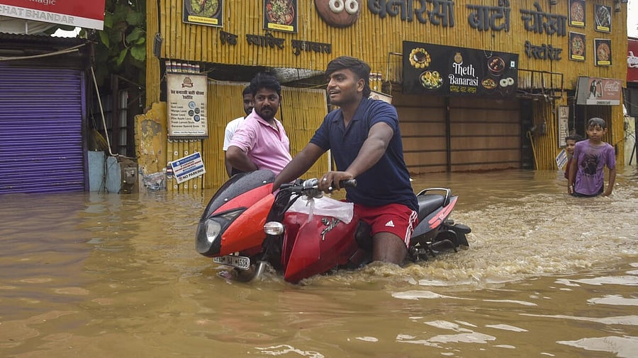 <div class="paragraphs"><p>People wade through an area inundated with water of the swollen Ganga river, in Varanasi, Uttar Pradesh.</p></div>
