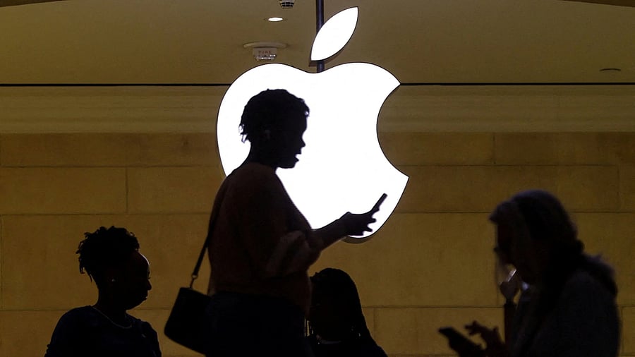<div class="paragraphs"><p>FILE PHOTO: A women uses an iPhone mobile device as she passes a lighted Apple logo at the Apple store at Grand Central Terminal in New York City.</p></div>