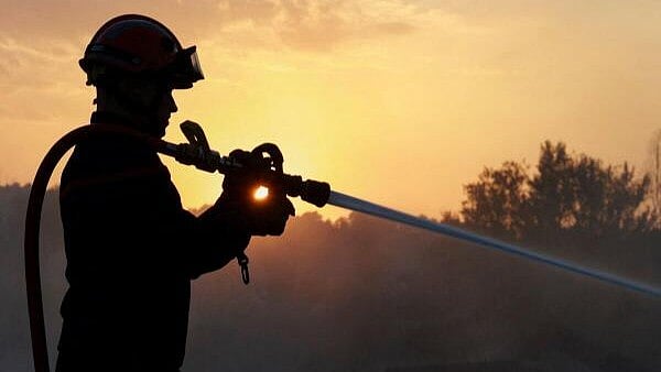 <div class="paragraphs"><p>A firefighter is silhouetted while conducting a water rescue operation at sunset amid land scorched by a wildfire near Saint-Laurent-de-la-Cabrerisse, southern France.</p></div>