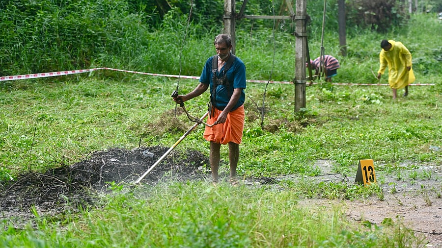 <div class="paragraphs"><p>Labourers remove the weeds grown at the 13th site as a preparation for the use of ground penetrating radar, in Dharmasthala police station limits on Monday.  </p></div>