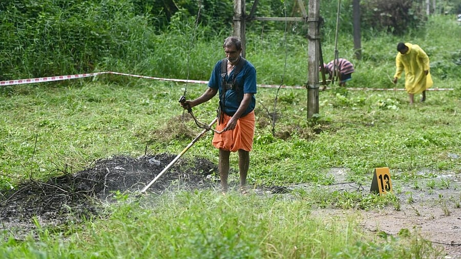 <div class="paragraphs"><p>Labourers remove the weeds grown at the 13th site as a preparation for the use of ground penetrating radar, in Dharmasthala police station limits on Monday. </p></div>