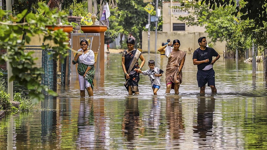 <div class="paragraphs"><p>People wade through a waterlogged road after heavy rainfall, at Mithali Nagar, Meerpet, Near Hyderabad, Telangana, Sunday, Aug. 10, 2025.</p></div>
