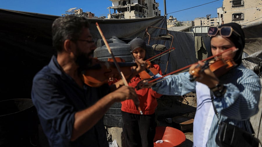 <div class="paragraphs"><p>Music instructor Ahmed Abu Amsha, 43, of the Edward Said National Conservatory of Music, conducts a lesson for Palestinian girls as a building damaged in the Israeli offensive appears in the background, in Gaza City, August 5, 2025. </p></div>